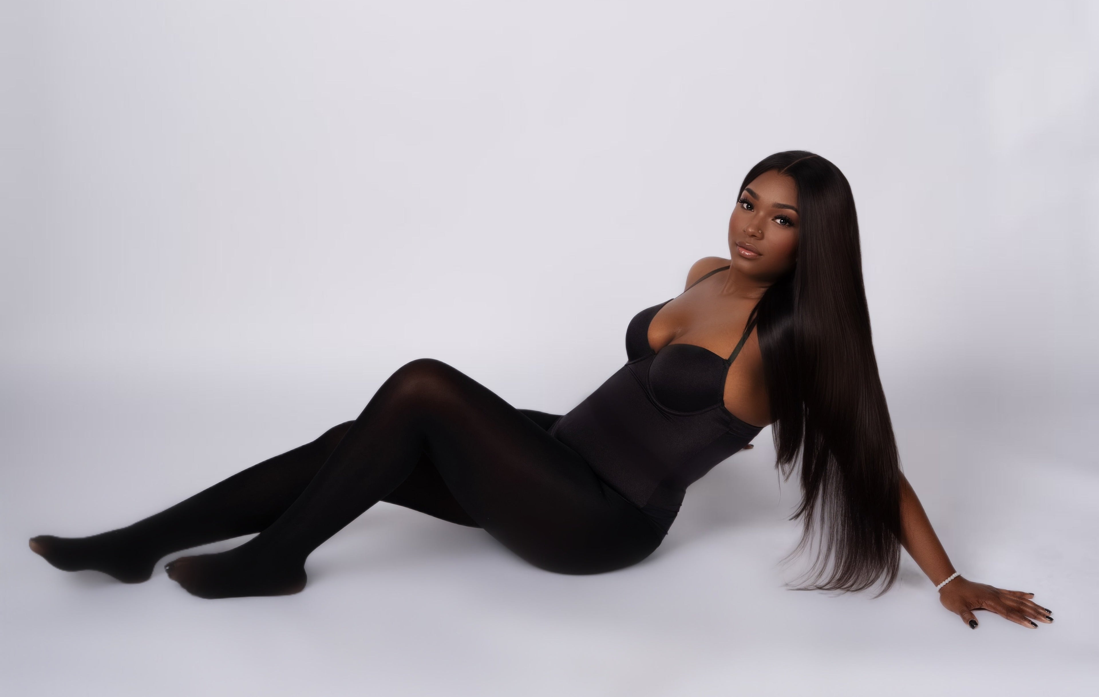 Woman in a black outfit sitting on a white background